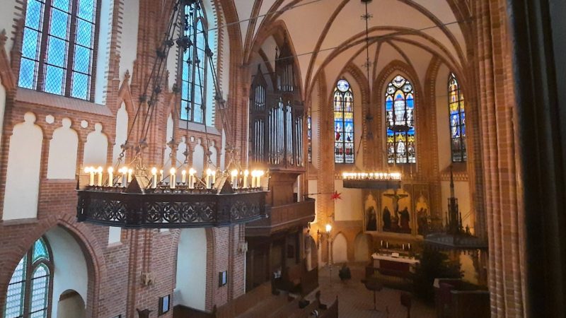 erleuchtete Kronleuchter an der Decke, im Hintergrund der Altar und die Orgel in der Klosterkirche Dobbertin