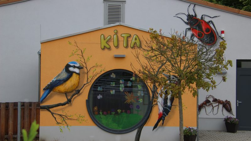 Seitenansicht Kita Dobbertin, Gebäude mit zwei großen Vögeln, einem Marienkäfer und Ameisen gestaltet